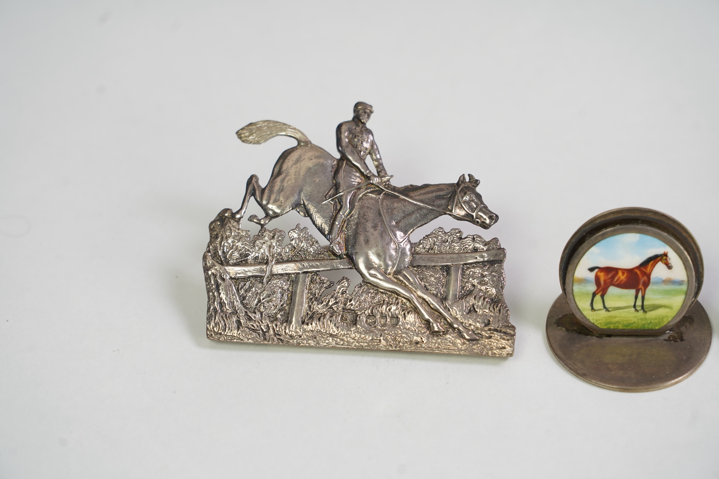 A pair of late Victorian silver menu holders, each modelled as a horse and rider leaping a fence, by Samuel Jacob, London 1894/5, height 66mm, together with a pair of Edwardian silver and enamel menu holders, each decora